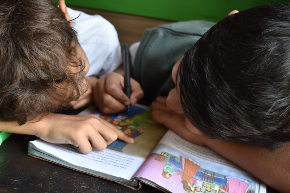 Two boys writing in a book.